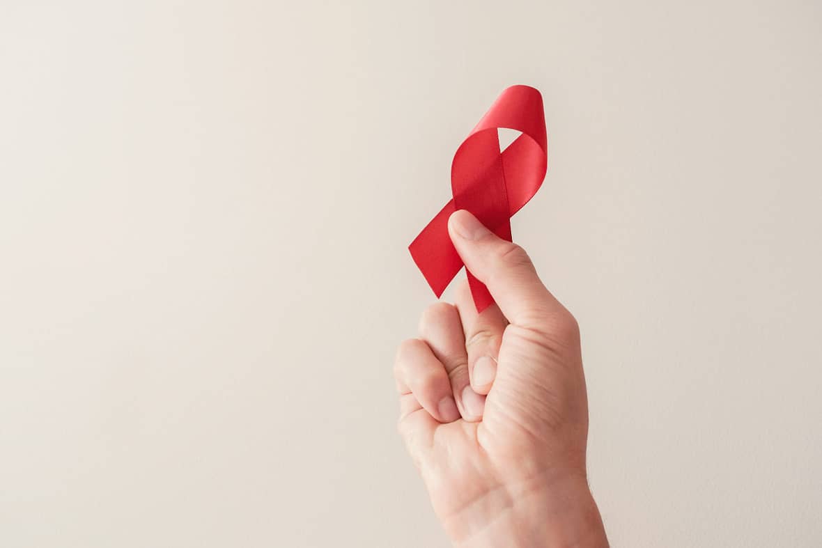 Hand holding red ribbon, hiv awareness concept, world AIDS day, world hypertension day