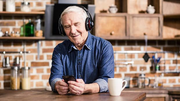 Switch it on. Pleasant smiling elderly man using his smartphone while listening to music